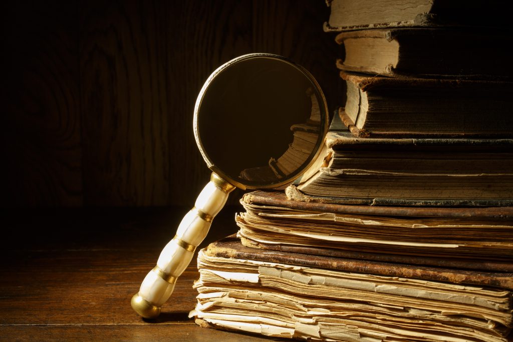 Lupă sprijinită pe un teanc de documente vechi