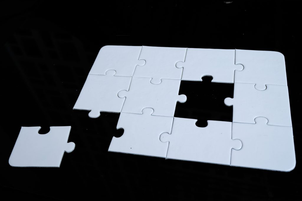Puzzle alb cu o piesă lipsă, pe fundal negru